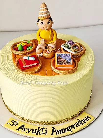 A cake to celebrate a sacred milestone, this design was for a baby's Annaprashan, or first rice ceremony. It features a hand-sculpted baby topper in a traditional Bengali topor, surrounded by symbolic items like the Bhagavad Gita, fruits, and kheer.