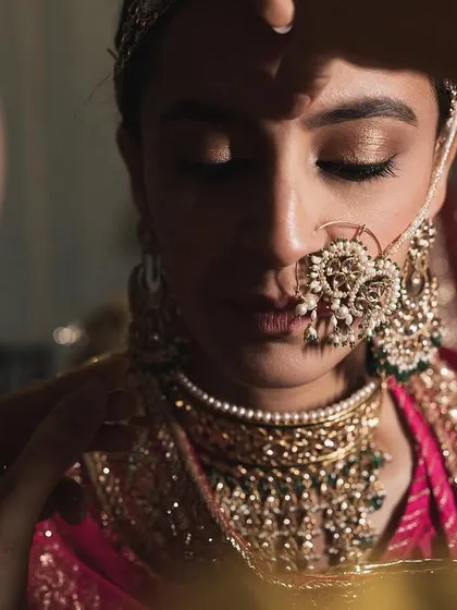 A behind-the-scenes moment of applying the bindi. The soft, shimmery eyeshadow and flawless skin are visible even in this intimate shot.
