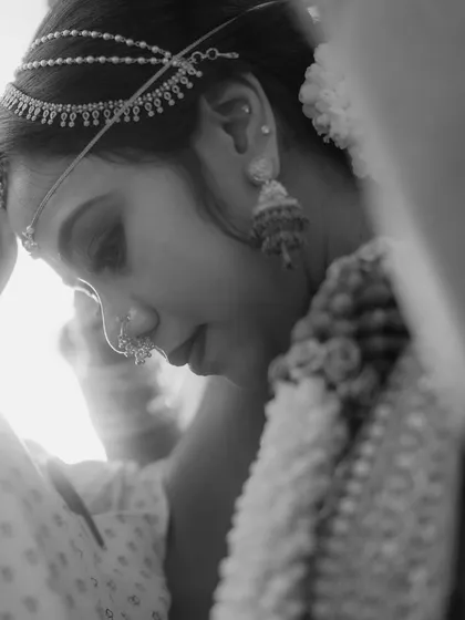 An intimate black and white close-up of the bride during a quiet moment in the ceremony. The focus on her delicate features and traditional jewelry creates a timeless and beautiful portrait.