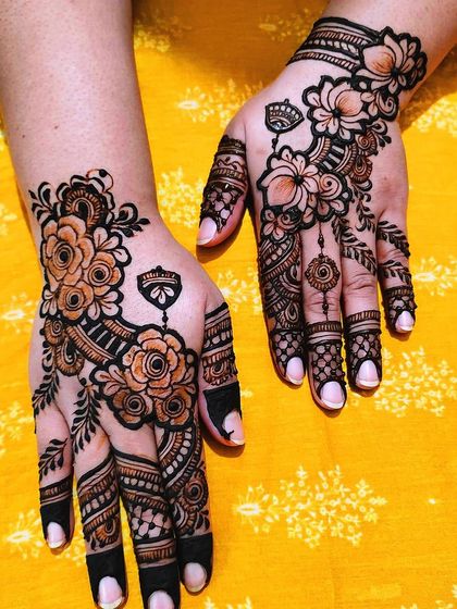 A matching set of Arabic floral mehndi on both hands. The design is asymmetrical but balanced, with a focus on bold flower outlines and delicate vine work.