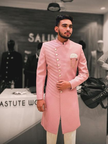 A client in a pink Indo-Western sherwani with a quilted texture and an asymmetrical button placket. The matching brooch adds a final touch of elegance.