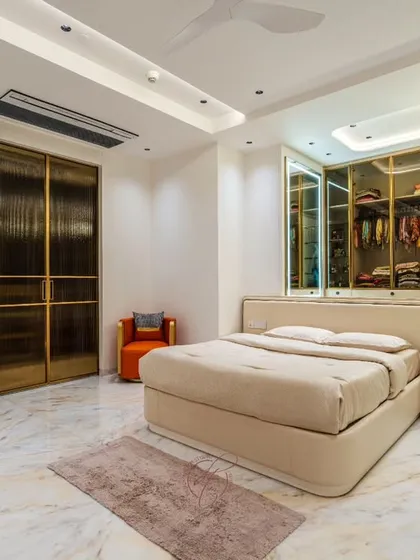 This angle shows the full scale of the room, with the plush bed, the elegant chandelier over the closet, and the beautiful veined marble flooring that adds a layer of opulence.