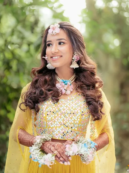 This bride's Haldi look is so dreamy. We designed her pastel floral jewellery using pink and blue orchids to add a delicate, modern charm to her vibrant yellow lehenga.