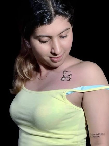 A small, cute baby elephant tattoo on the collarbone.