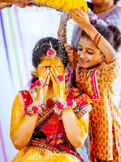 A heartwarming moment as a young family member joins in to shower the bride with flowers and water.