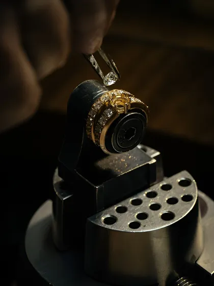 From the hands of skilled artisans to the final creation, every detail matters. This image shows the delicate process of setting a diamond into a ring, a testament to a legacy of fine craftsmanship and passion.