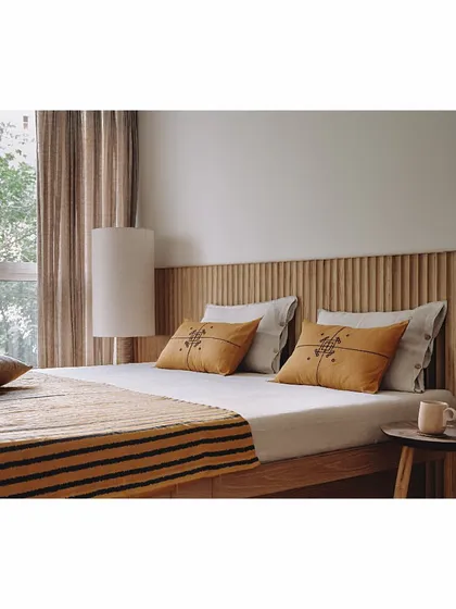 This bedroom for a mother is clad in a hand-carved oak wood headboard, adding a touch of natural elegance. We used offcuts of plywood from the site to design a unique, totem-like floor lamp, turning leftover material into a beautiful, functional art piece.