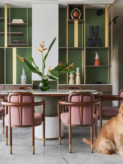 A full view of the dining setup, featuring the 'Pellet drum' table and 'Svelte' chairs against a backdrop of custom green and brass shelving. The design is both functional for family meals and beautiful for entertaining.