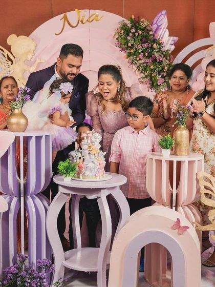 The whole family gathers for the cake-cutting at Nia's butterfly-themed party, surrounded by whimsical fairy and butterfly decorations.
