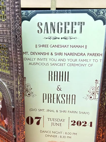 A Sangeet invitation is revealed as the intricate, laser-cut doors of the card are opened, creating a moment of anticipation and delight.