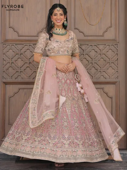 This pastel pink lehenga with heavy silver and green embroidery is a sophisticated choice for a wedding guest or bridesmaid. It's paired with a beautiful green necklace.