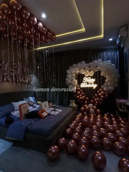 A wide-angle view of a romantic bedroom decoration, with a heart-shaped balloon arch and 'Happy Birthday' foil balloons.