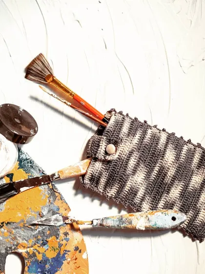 Our crochet utility pouch is incredibly versatile. Here, it's being used to hold art supplies like brushes and palette knives, keeping them organized and protected.
