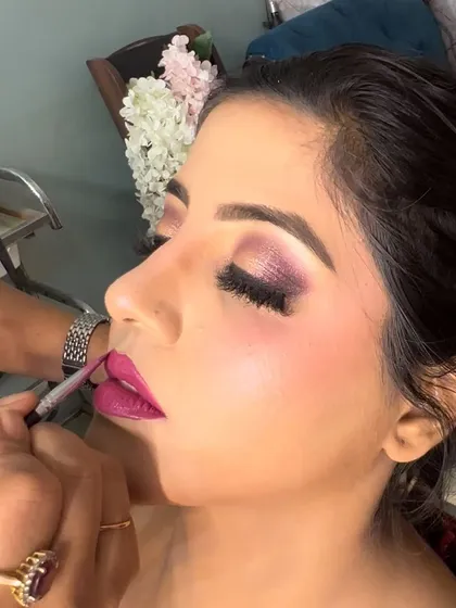 A close up of the lip application process for a bold pink lip.