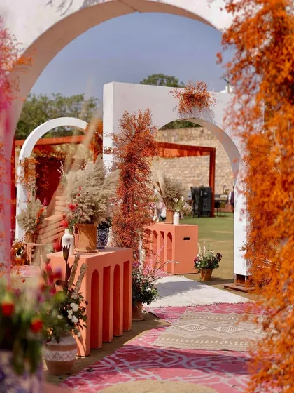 An inviting entrance to the rust-orange Haldi, with a pathway through modern arches and decor elements that blend rustic textures with a contemporary color palette.