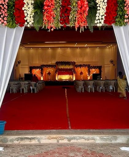 This is the main entrance to a large reception hall we decorated. The grand pillars are draped in white fabric and topped with a heavy floral arrangement, creating an impressive entryway for the event.
