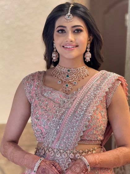 A happy bride in a beautiful pink lehenga for her reception. The makeup is glamorous yet soft, with diamond jewelry adding a touch of sparkle.