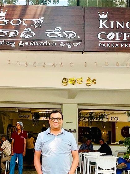Our consultant pictured at a bustling King's Coffee Co. cafe. This showcases the vibrant atmosphere and customer appeal of the brand we are helping to franchise.