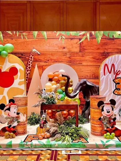 Welcome to a Mickey Mouse jungle safari adventure! This expansive backdrop brings the wild indoors with a wood-paneled wall, lush balloon garlands in earthy tones, and beloved characters like Mickey and Pluto ready for exploration. It's a perfect example of how I transform a space into a story.