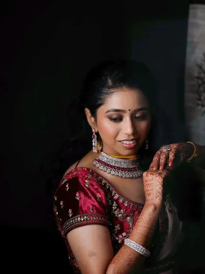 A more artistic portrait from the reception. The soft lighting highlights the flawless finish of her makeup and the richness of her velvet blouse.