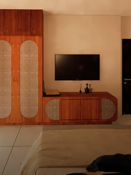 To maximize floor space, I designed a custom media unit that combines a TV console with a sleek, rattan-paneled wardrobe. This integrated approach keeps the room feeling uncluttered and spacious.