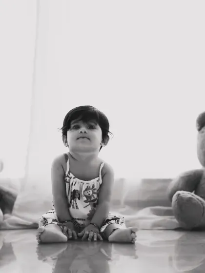 A simple, classic portrait of a baby sitting between two teddy bears. The black and white treatment gives it a timeless, nostalgic quality.