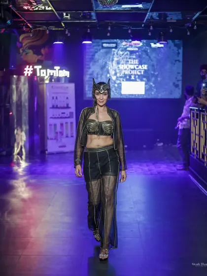 The full runway walk of the sheer black and gold outfit, showing its presence in a club-like, atmospheric setting.
