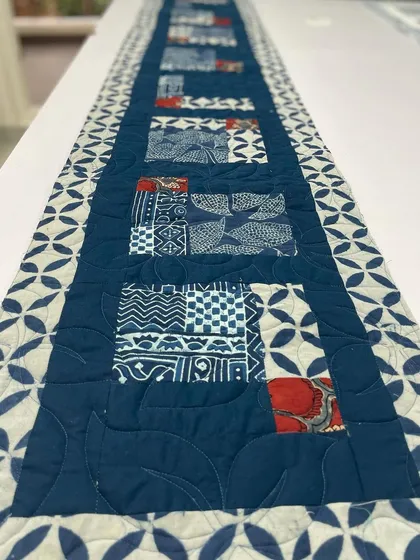 Another beautiful table runner, also using indigo fabrics with touches of red.