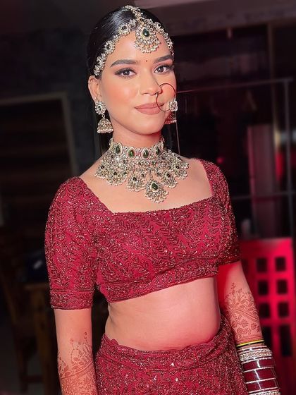 A full-body shot showing the sleek, modern bridal bun and how it balances the heavy jewelry and intricate lehenga. It’s a sophisticated and polished look.