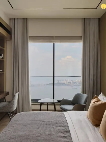 A bedroom designed as a quiet corner with a view. The seating nook by the window provides a perfect spot for reading or simply watching the city below, making the most of the apartment's high-rise location.