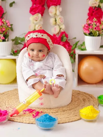 A wide shot of the Holi mini-session setup, showing the colorful powders, balloons, and a happy baby ready to celebrate.