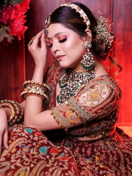 A close-up of the bride's look, showing the intricate green and polki jewellery against the red of the lehenga.