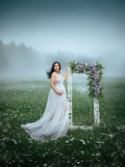 The wind catching her hair and dress adds a dynamic and wild element to this misty field portrait. It’s a beautiful capture of motherhood's powerful and natural essence.