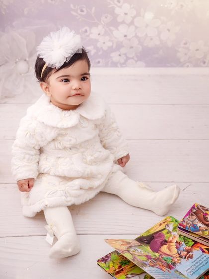 A baby girl is a miracle. This little one, dressed in a cozy white outfit, looks so peaceful during her sitter session.