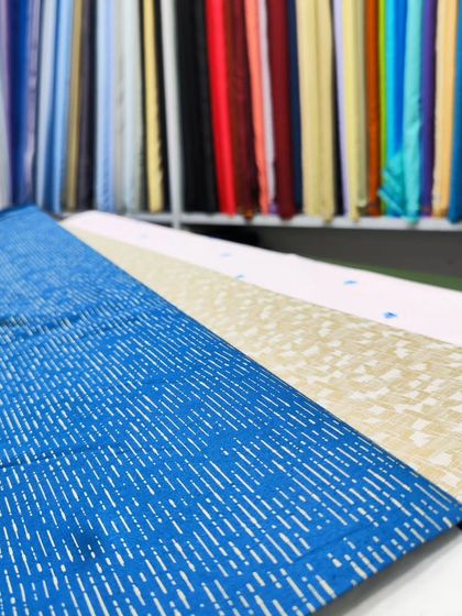 A selection of premium fabrics available in my studio for custom-made shirts and kurtas, showing a variety of prints and weaves.