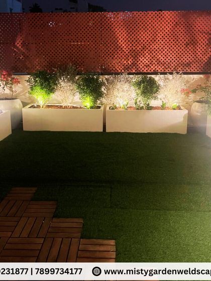 Another view of the Banashankari terrace, showing the lush artificial grass and the warm glow from the planter lights. The space is designed to be a green retreat above the city.
