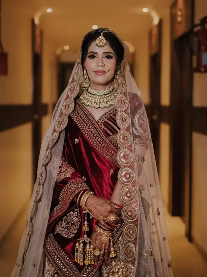 A full-length portrait in a hallway, showcasing the grandeur of her bridal lehenga and the elegance of her posture.