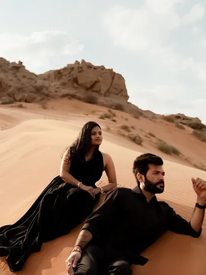 A candid portrait of the couple relaxing on a sand dune in Dubai. The natural pose and the expansive desert backdrop make for a stunning and authentic elopement photo.