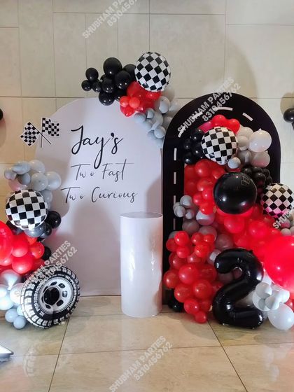 A creative "Two Fast Two Curious" car racing theme for a second birthday, with a race track balloon arch and checkered flag details.