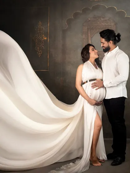 A beautiful moment between partners. I love capturing these intimate connections, with the flowing white gown adding a touch of elegance and drama to this maternity couple portrait against a classic studio backdrop.