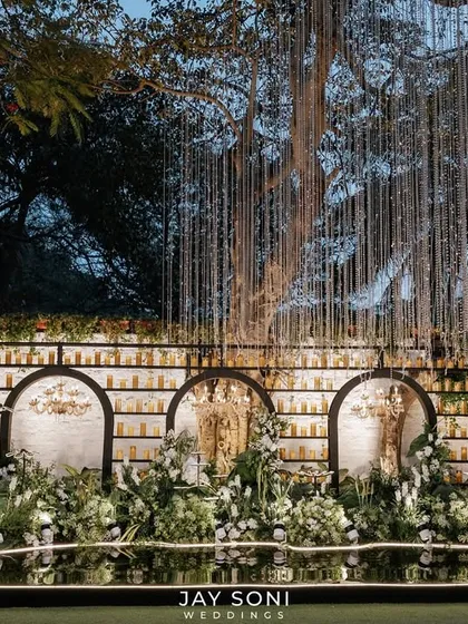 This engagement stage combines modern elegance with romantic ambiance. I designed a striking backdrop featuring a wall of candles set within dark arches, complemented by lush white and green florals and cascading string lights for a truly captivating effect.