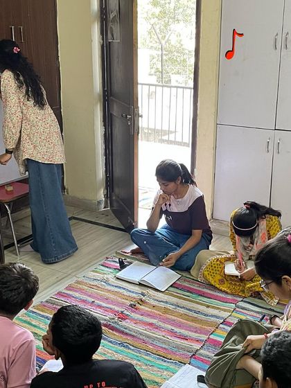 A student writes on the whiteboard, taking on the role of a teacher for her peers. This practice builds confidence and reinforces her own learning.