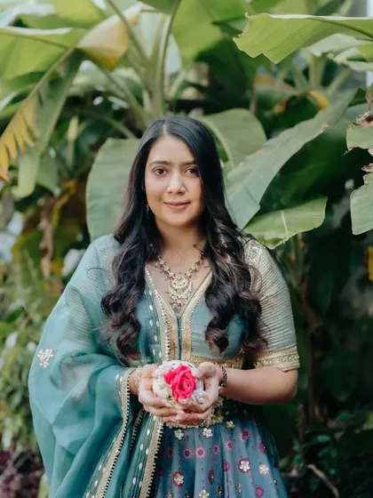 A beautiful portrait from the first wedding function. The makeup is kept fresh and radiant, letting her natural beauty and the vibrant flowers she's holding shine.