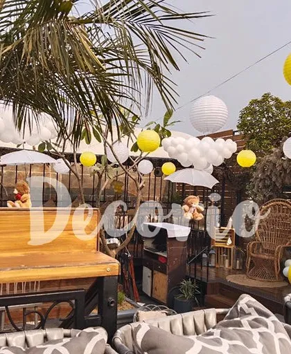 An overview of an outdoor baby shower venue I decorated. I used hanging paper lanterns and balloon clouds to decorate the space, creating a festive and cohesive look throughout the area.