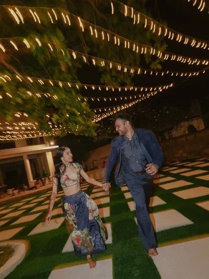 A candid shot of a couple running barefoot and laughing under a canopy of fairy lights in Kenya. This image is full of joy, movement, and the magic of a warm evening celebration.
