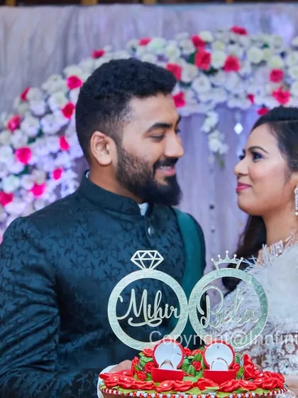 The couple posing with their engagement cake, which features a custom topper with their names. This shot highlights the personalized details of their celebration.