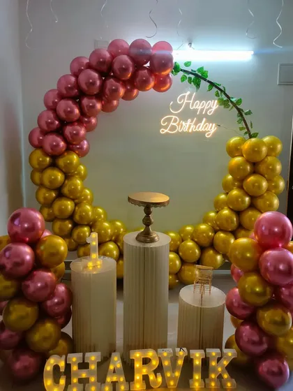 A chic pink and gold metallic balloon arch with a neon sign and modern pedestals.