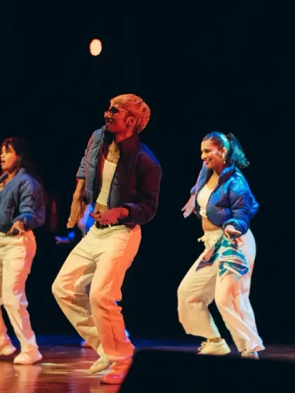 A dynamic shot of three dancers mid-performance, captured in perfect sync under the professional stage lighting.