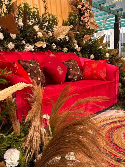 A close-up of the boho seating area, highlighting the textures of the pampas grass, the plush velvet sofa, and the rustic jute rug.