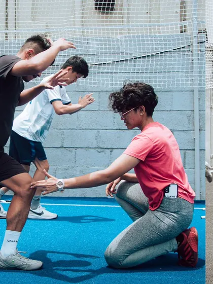 A coach providing hands-on correction to a youth athlete's form during an agility drill. This demonstrates our commitment to teaching proper movement mechanics from a young age.